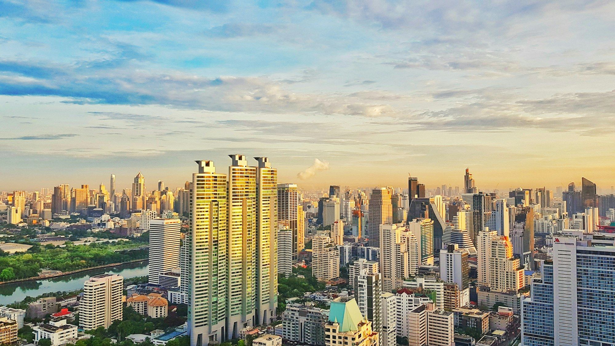 Bangkok skyline of high-rise towers beside the Chao Phraya river at golden hour
