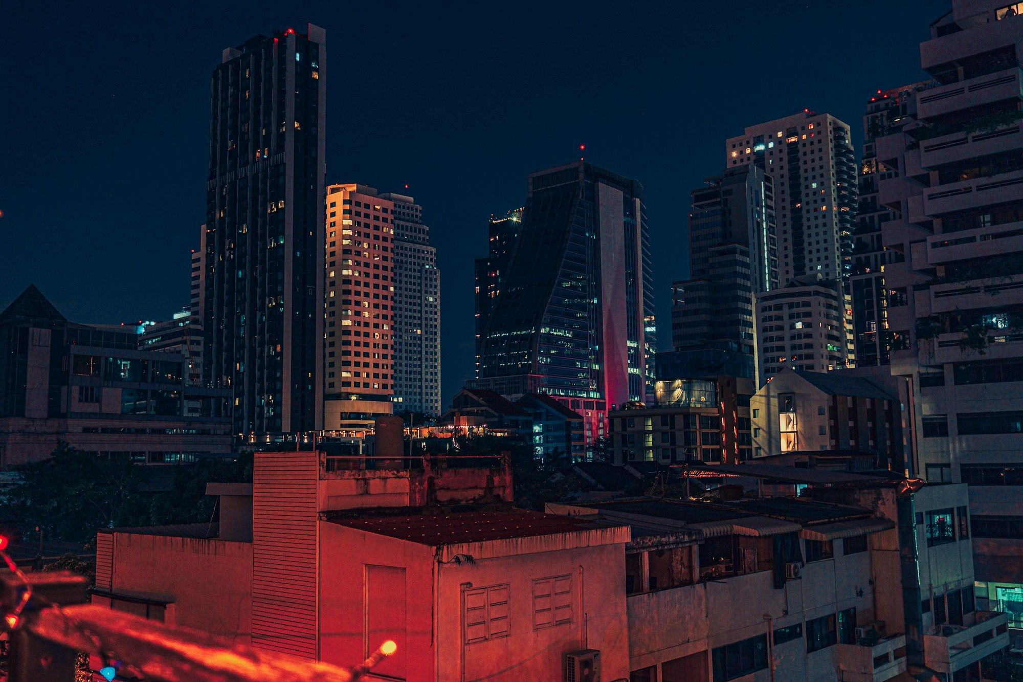 Bangkok street at night with neon signs and traffic light trails